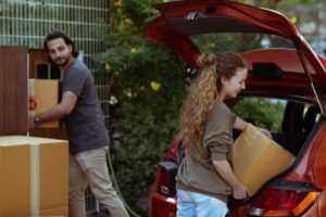 two persons moving boxes in a car