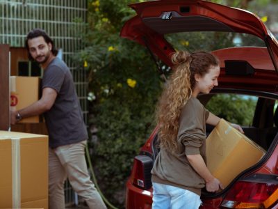 two persons moving boxes in a car